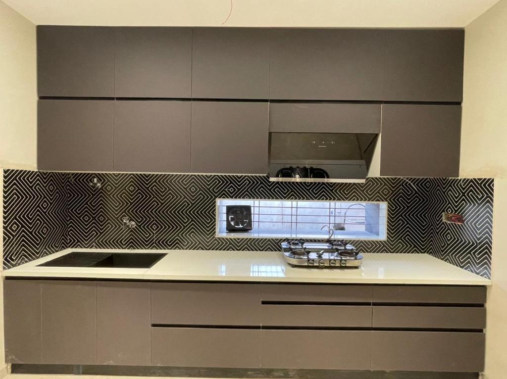 Handleless white modular kitchen in Aurangabad with chimney and quartz countertop by More Than Kitchen
